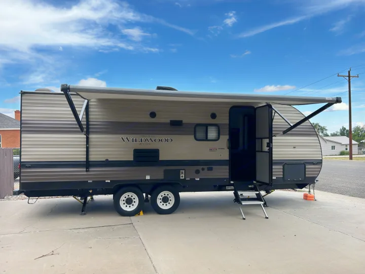This Forest River Wildwood X-Lite travel trailer rv rental is set up with its awning out and door open, ready for use.. Forest River Wildwood Cruise Lite 2019