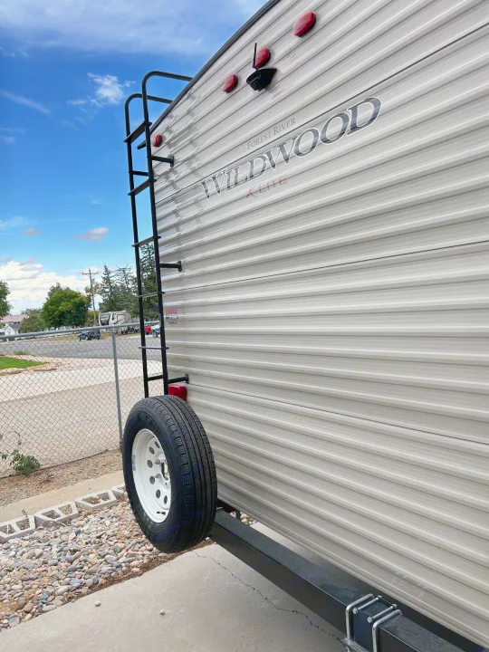 Rear of Forest River Wildwood travel trailer with ladder & spare tire. Perfect for your RV rental journey.. Forest River Wildwood Cruise Lite 2019