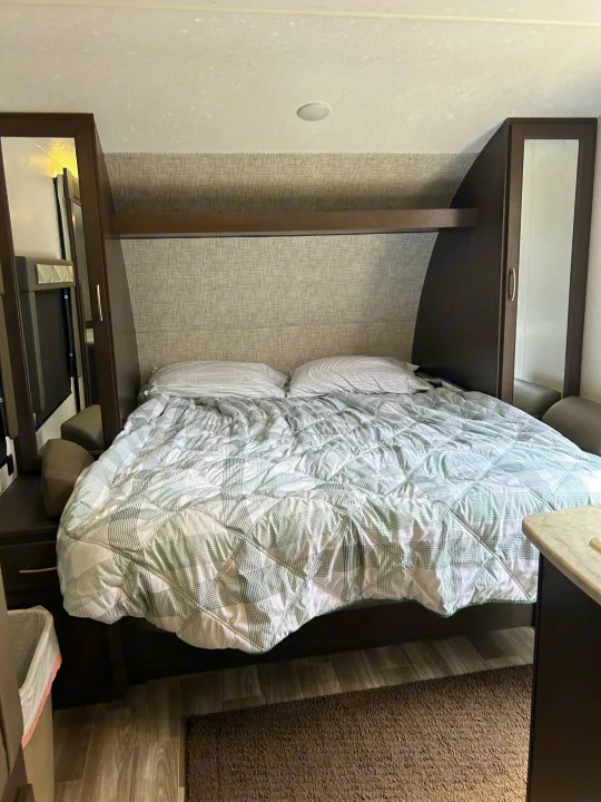 Cozy RV rental bedroom with comfortable bed and built-in storage, ideal for travel lodging.. Forest River Wildwood Cruise Lite 2019