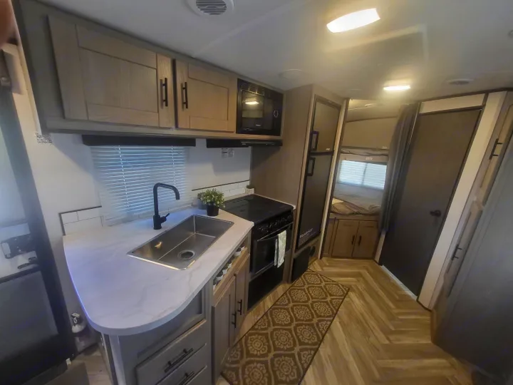 RV rental interior: modern kitchen with sink, stove, microwave, fridge, plus cozy bunk beds & stylish herringbone flooring.. Cruiser Rv Corp Shadow Cruiser 2021