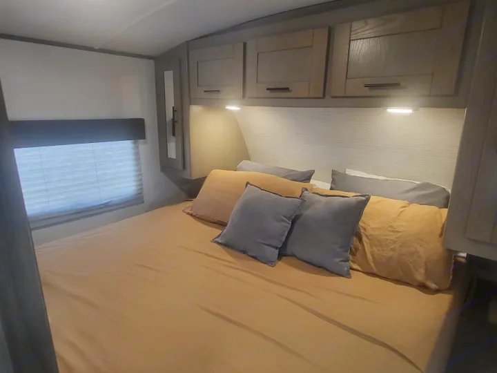 Comfortable RV rental bedroom featuring a bed with mustard yellow bedding, gray pillows, and overhead cabinets.. Cruiser Rv Corp Shadow Cruiser 2021