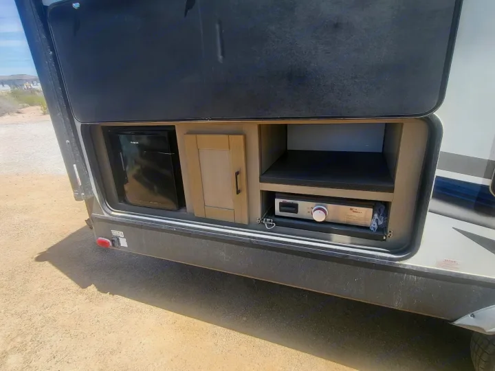 This RV rental's exterior kitchen features a mini-fridge, wood cabinet, and pull-out griddle for outdoor cooking.. Cruiser Rv Corp Shadow Cruiser 2021