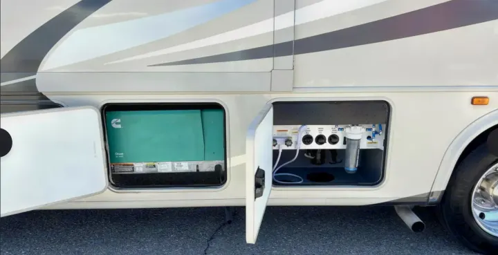This RV rental shows its open generator compartment and utility bay with water filter and various hookups.. Forest River Other 2021
