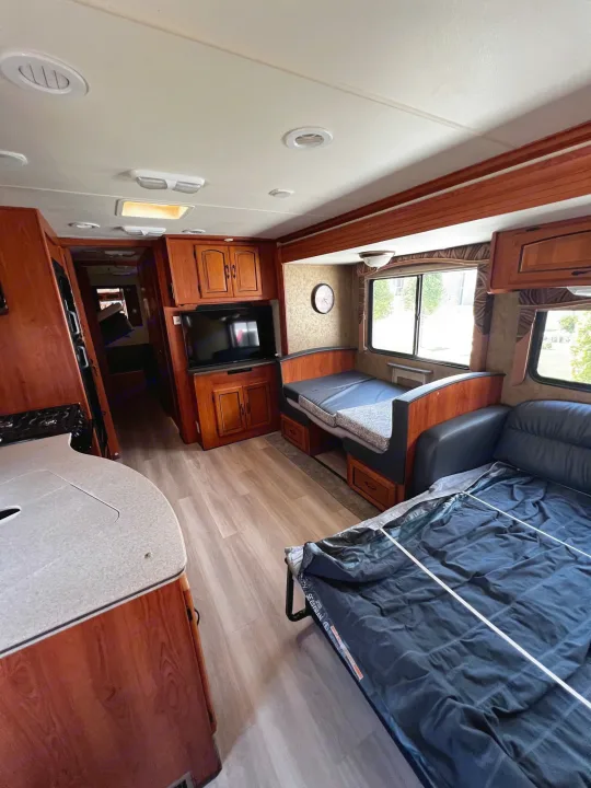 Spacious RV rental interior featuring a kitchen counter, entertainment center, and comfortable seating that converts to a bed.. Forest River Coachmen Mirada 32 DSF 2011