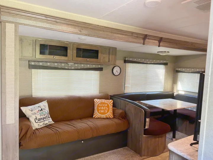 Cozy rv rental living space with a brown sofa, dining booth, and overhead storage.. Dutchmen Aspen Trail 2019