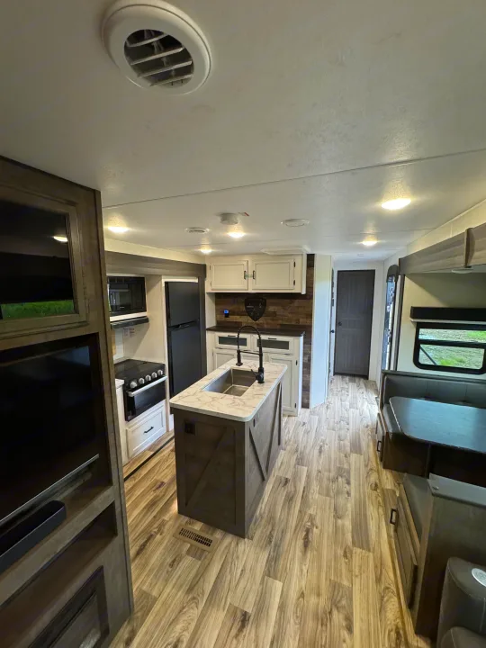 Bright RV rental interior with kitchen island, dinette, and entertainment center.. Venture RV 327VIK 2024