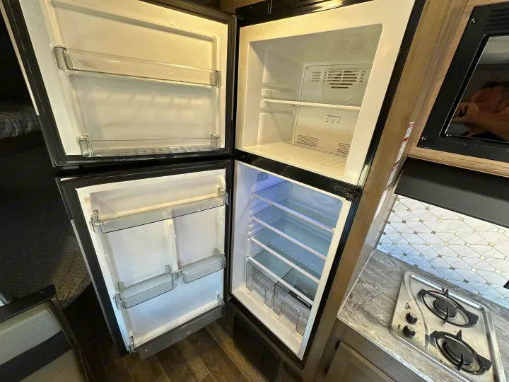 Clean RV rental kitchen: empty top-mount fridge/freezer and two-burner stove. Ready for your adventures!. Gulf Stream Kingsport 2022