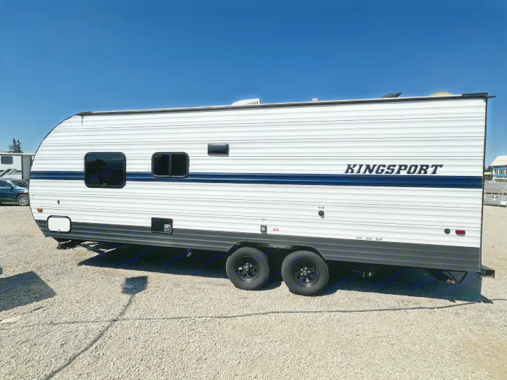 White Kingsport RV rental with a blue stripe, parked on gravel under a clear blue sky.. Gulf Stream Kingsport 2022