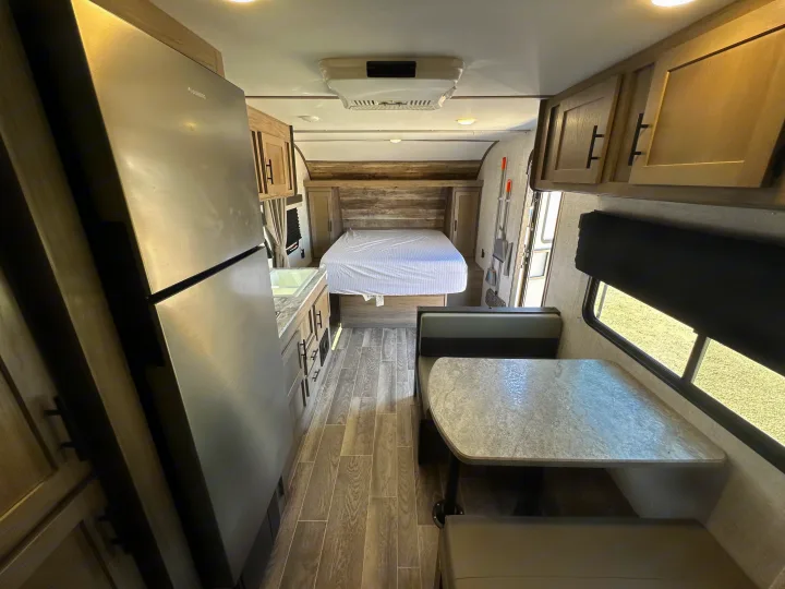 Interior of an RV rental, showcasing a compact living space with a full kitchen, dining area, and a rear bedroom.. Gulf Stream Kingsport 2022