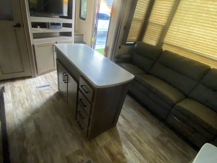 Spacious modern RV rental interior with kitchen island, living area, and entertainment center.. Keystone Carbon 2020
