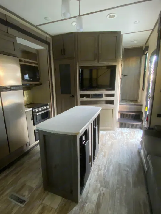 Experience this RV rental's interior: kitchen with fridge & stove, central island, entertainment center with TV, and rear steps.. Keystone Carbon 2020
