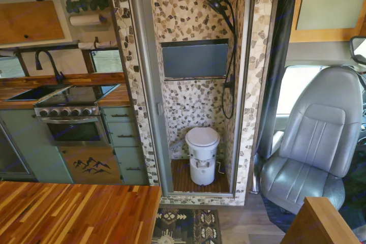Inside an rv rental: wood kitchen, tiled shower with toilet, and driver's seat. Compact living for adventures.. Chevrolet Express 2011