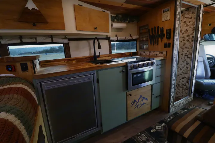An RV rental's detailed interior shows a full kitchen with stove, fridge, wood counters, sink, and a tiled shower.. Chevrolet Express 2011