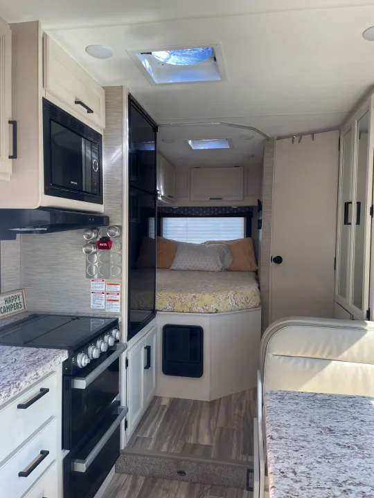 Step inside this Avis **RV rental**, featuring a compact **kitchen** with a **microwave** and **oven**, plus a **cozy bedroom** at the rear.. Thor Freedom Elite 2022