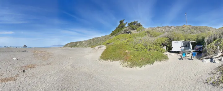 Serene beach campsite features an RV rental, chairs, and scenic ocean views under a blue sky.. Gulf Stream Enlighten 2021