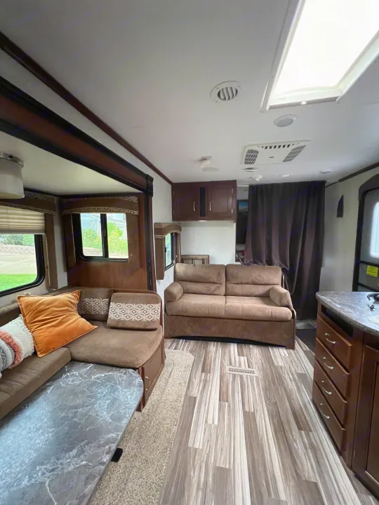 Enjoy this inviting RV rental living area! Features L-shaped sofa, wood flooring, kitchen counter, and bright windows.. Jayco Jay Flight 2014