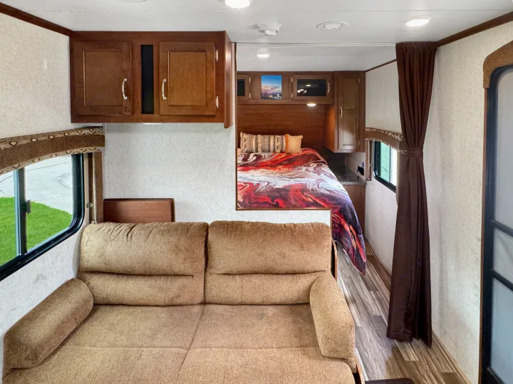 Spacious RV rental interior: view from a comfy sofa looking towards the bedroom with a colorful comforter and cabinets.. Jayco Jay Flight 2014