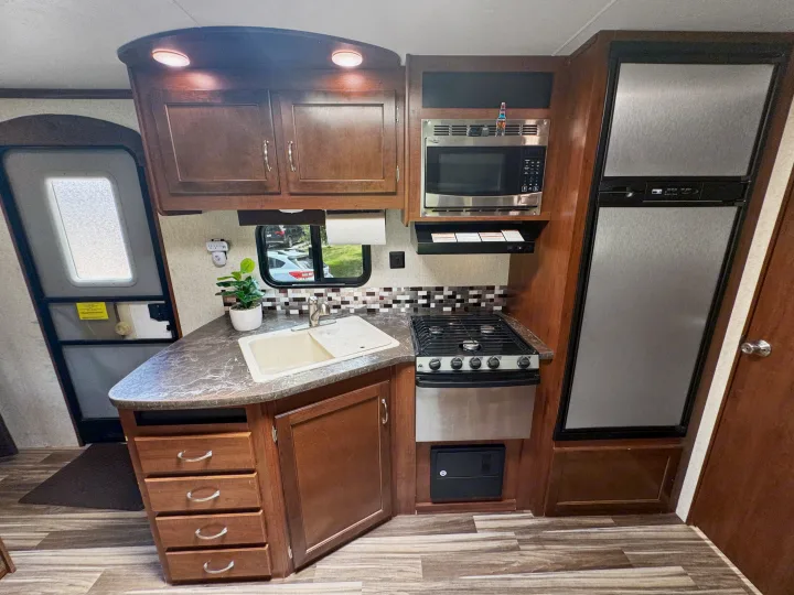 Step into this modern RV rental kitchen: full amenities like sink, stove, microwave, fridge, and storage cabinets.. Jayco Jay Flight 2014