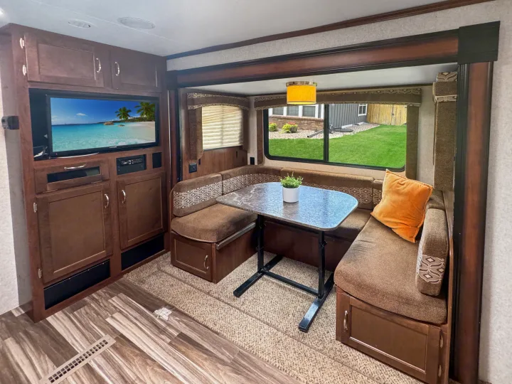 Spacious RV rental interior featuring a comfortable dinette, entertainment center, and scenic window views.. Jayco Jay Flight 2014