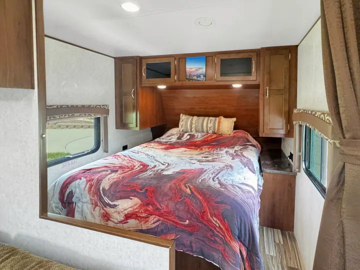 This RV rental features a cozy bedroom with colorful bedding, built-in cabinets, and a window for natural light.. Jayco Jay Flight 2014