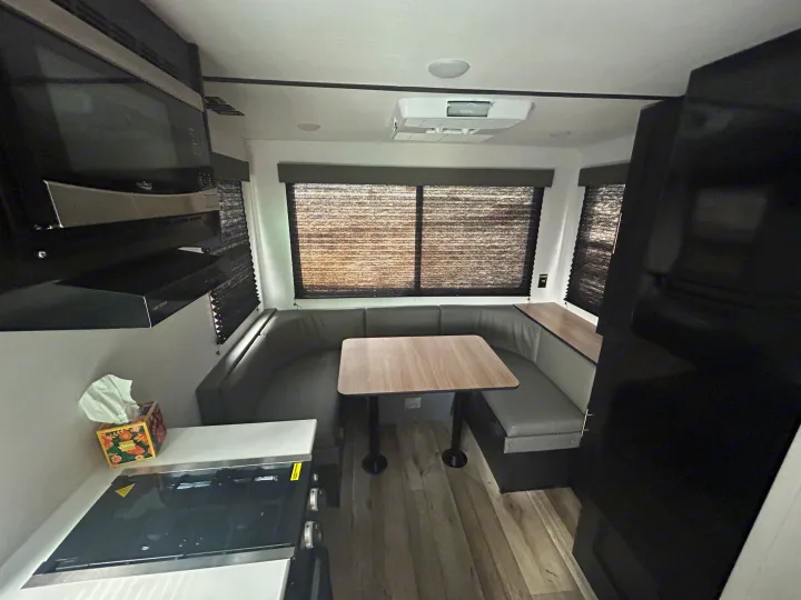 Spacious rv rental camper interior featuring a kitchen with microwave, stovetop, and a comfortable U-shaped dinette.. Keystone RV Springdale 2023