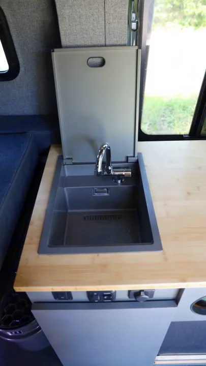 This RV rental showcases a clever, compact kitchen: a gray sink with a lift-up cover, chrome faucet, and bamboo counter.. Mercedes-Benz Sprinter 2024