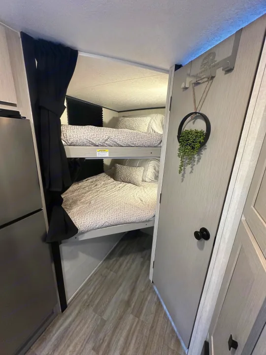 Cozy RV rental bunk beds with privacy curtains and modern decor, perfect for family camping trips. Life is better at the campsite!. Coachmen Apex Nano 2024