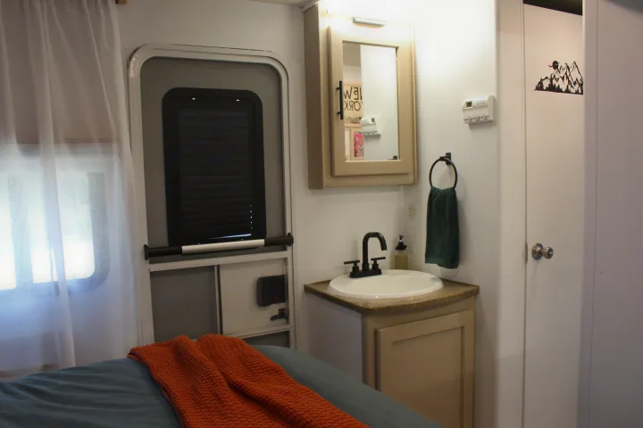This RV rental's compact interior features a cozy bed, sink vanity, and windowed entry door.. Lance Manufacturing Lance Manufacturing Trailer 2015