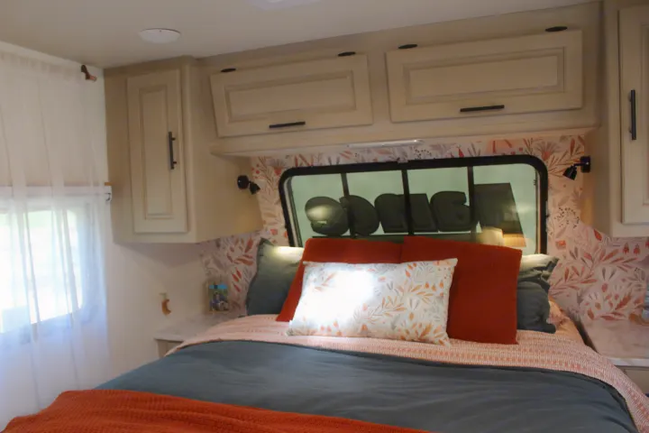 This inviting RV rental bedroom offers a comfortable bed, stylish floral wallpaper, and ample overhead storage.. Lance Manufacturing Lance Manufacturing Trailer 2015