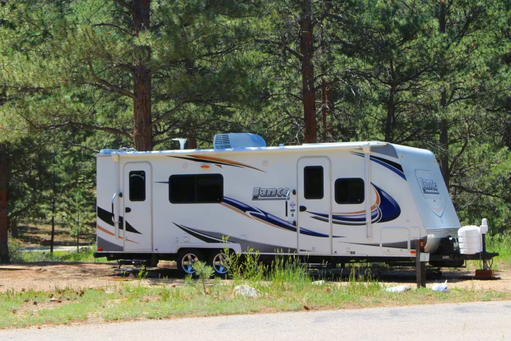 Lance travel trailer RV rental parked at a peaceful pine tree campsite.. Lance Manufacturing Lance Manufacturing Trailer 2015