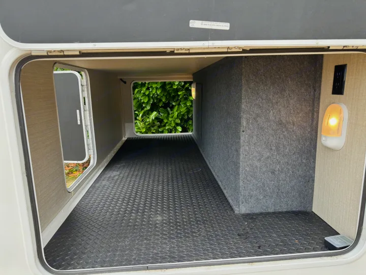 Inside a clean RV rental's pass-through storage: durable floor, power outlet, and bright light for convenient loading.. Jayco Redhawk SE 2019