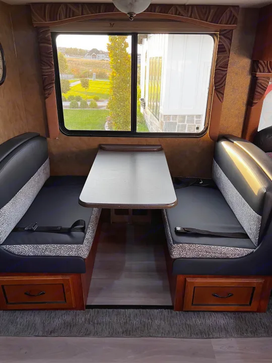 RV rental dinette: comfortable bench seating, practical table, and a bright window with a view. Perfect for meals on the go.. Forest River Coachmen Mirada 32 DSF 2011