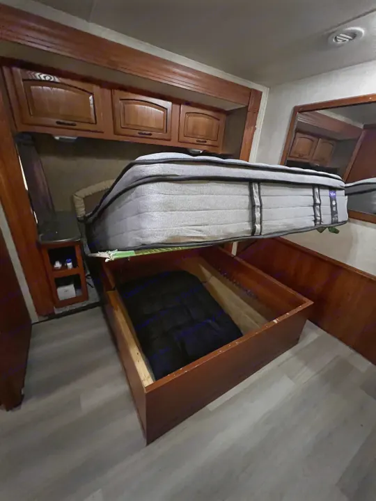 RV rental bedroom with clever under-bed storage revealed. Mattress lifted to access hidden space for travel gear.. Forest River Coachmen Mirada 32 DSF 2011