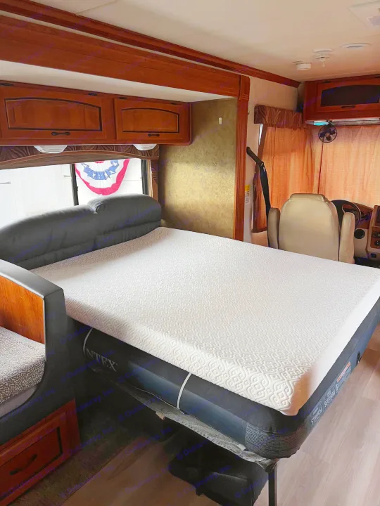 RV rental: Brightly lit interior showcasing a convertible air mattress bed, wood cabinets, and front seats.. Forest River Coachmen Mirada 32 DSF 2011