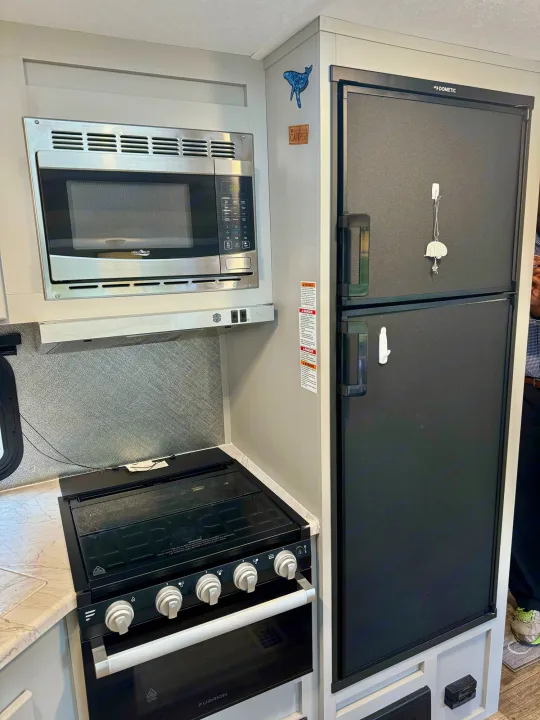 Inside an rv rental: a well-equipped kitchen featuring a High Pointe microwave, Furrion stove, and Dometic refrigerator.. Forest River Vibe 2021
