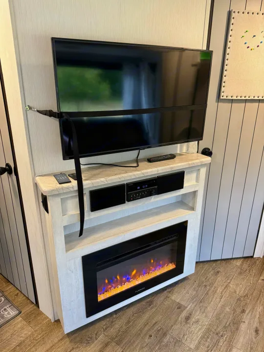RV rental's modern interior: TV secured above an electric fireplace and sleek media console.. Forest River Vibe 2021