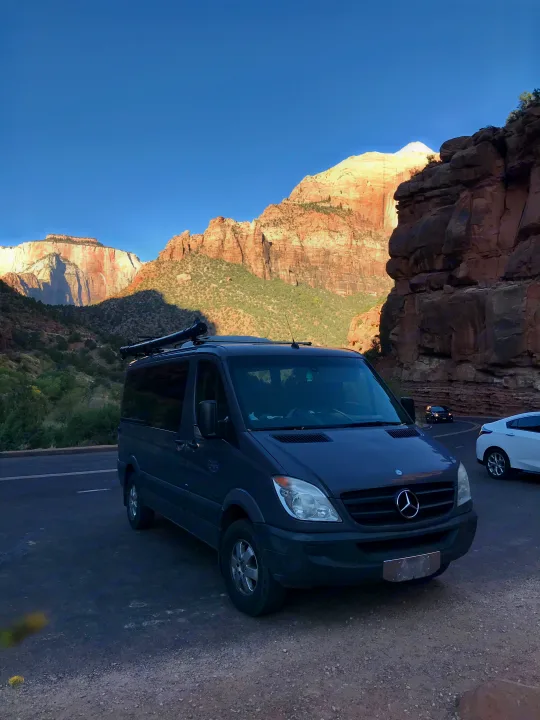 Dark grey RV rental (Mercedes Sprinter) parked with stunning red rock mountains & clear blue sky background.. Mercedes Sprinter 2011