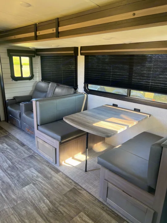RV rental living area: features comfy grey recliners, a dinette with benches, and sleek wood-look flooring.. Crossroads sunset trail superlite 2022