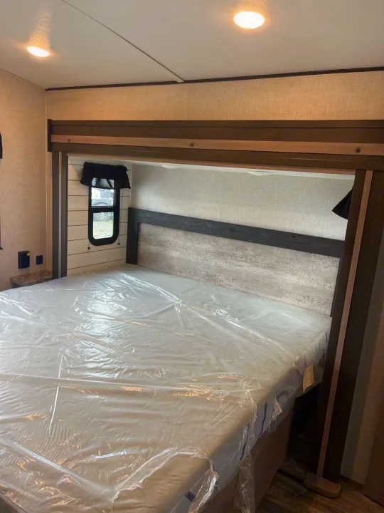 Ready for your trip: This RV rental bedroom features a queen bed wrapped in plastic, modern headboard, window, and convenient side outlets.. Crossroads sunset trail superlite 2022