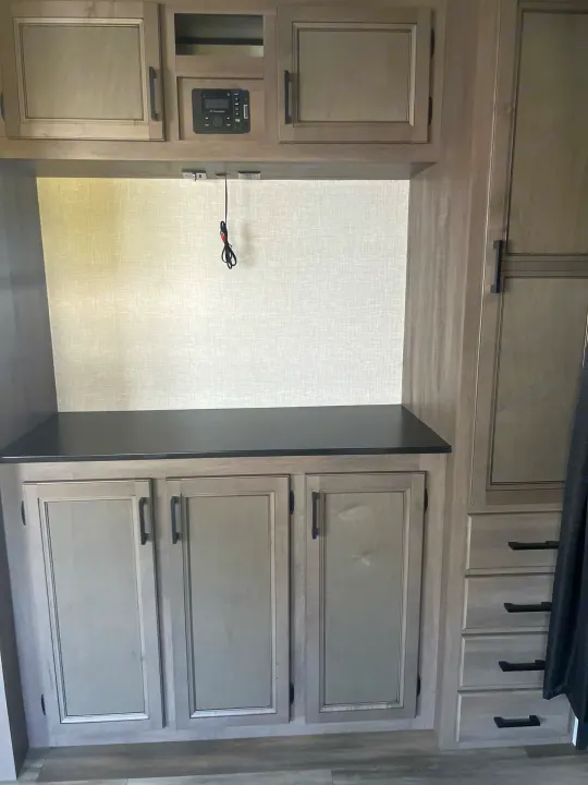 Spacious RV rental interior showing light woodgrain cabinets, dark counter, built-in media system, and outlets.. Starcraft Autumn Ridge 2023