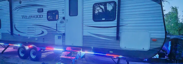 Nighttime view of a Wildwood RV rental illuminated by colorful LED lights, perfect for camping trips.. Forest River Wildwood 2014