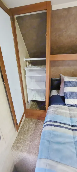 RV rental bedroom: Compact closet with hanging organizer and cozy striped bed.. Forest River Wildwood 2014
