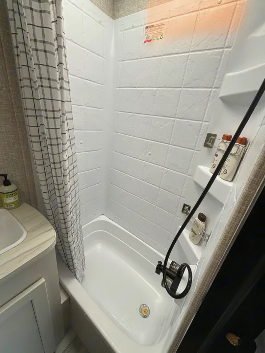 Experience comfort in your rv rental with this clean RV shower. Features a compact tub, plaid curtain, & organized bath essentials.. Jayco Jay Flight SLX 2024