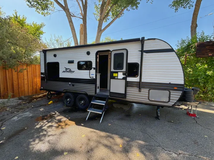 A white and grey Jay Flight travel trailer (RV rental) is parked with its door open and steps extended, ready for adventure.. Jayco Jay Flight SLX 2024