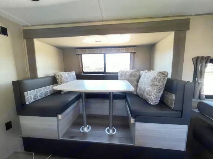 Clean RV rental interior featuring a cozy booth dinette with patterned pillows and a table, perfect for meals on the go.. Coachmen Catalina 2022