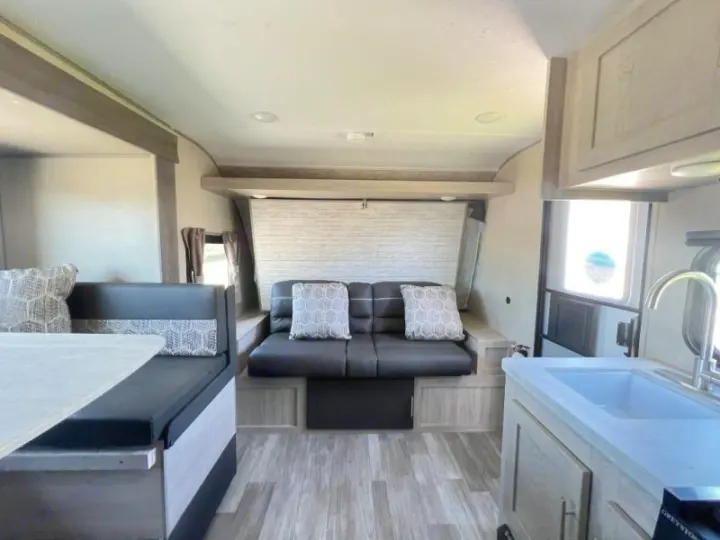 Spacious RV rental interior featuring a kitchen, dining booth, and convertible sofa/bed. Ideal for comfortable travel.. Coachmen Catalina 2022