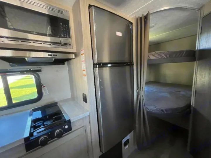 RV rental interior: well-equipped kitchen featuring microwave, stove, and fridge, adjacent to cozy bunk beds.. Coachmen Catalina 2022