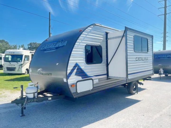 A modern grey Coachmen Catalina travel trailer with a pop-out and propane tank. Ready for your next rv rental camping trip at an RV lot.. Coachmen Catalina 2022