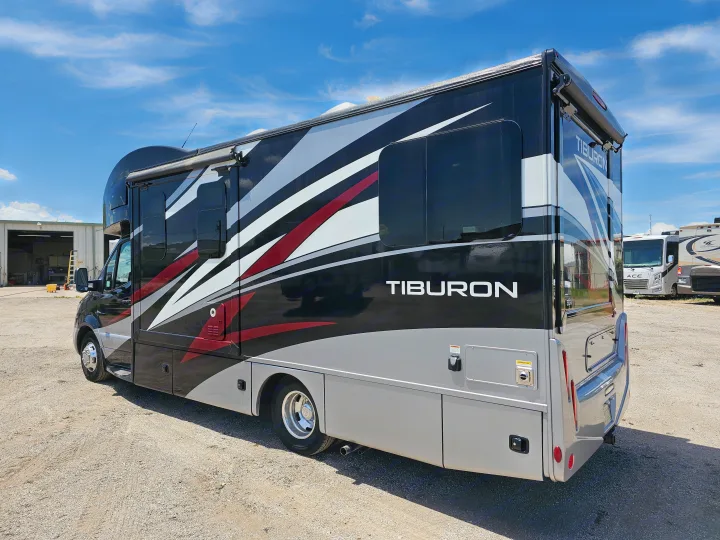 Stylish black, gray, and red Tiburon RV rental, with dynamic stripes, parked on a sunny gravel lot, ready for adventure.. Thor Motor Coach Other 2023