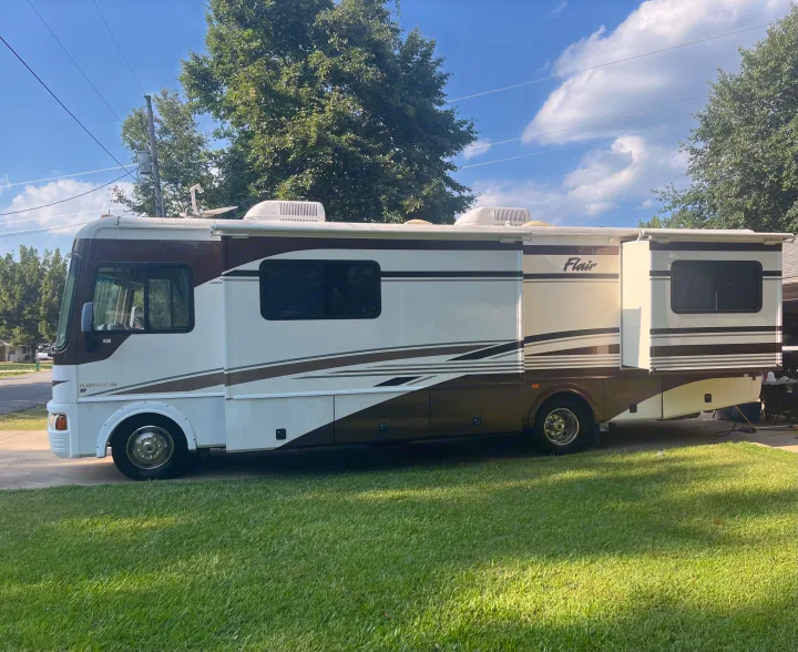 A large Fleetwood Flair motorhome parked on a driveway, ideal for an RV rental. Ready for travel in sunny weather.. Fleetwood Flair 31A 2005